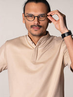 polo Simba beige porté par Esteban